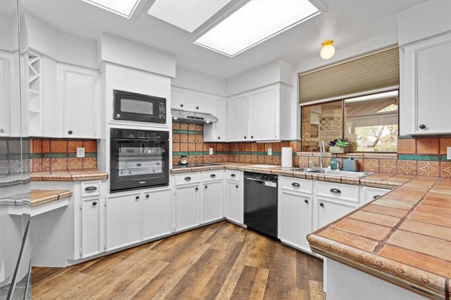 Kitchen with sink, white cabinets, black appliances, and tile counters | Image 13