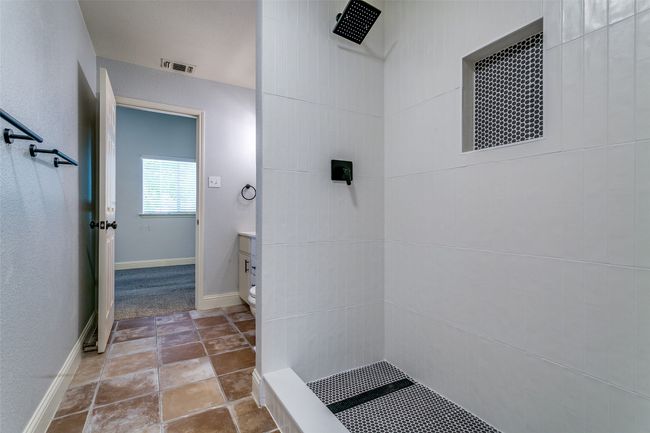 Full bath featuring tiled shower, stone finish floors, and vanity | Image 20