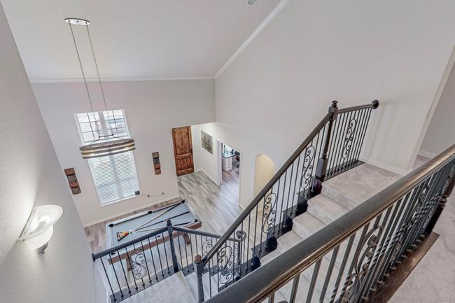 Staircase featuring a high ceiling, ornamental molding, baseboards, and carpet flooring | Image 33