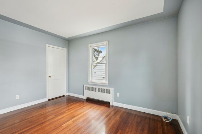 Unfurnished room featuring radiator, wood finished floors, and baseboards | Image 14
