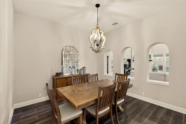 Dining space with dark wood-type flooring, a chandelier, and baseboards | Image 19