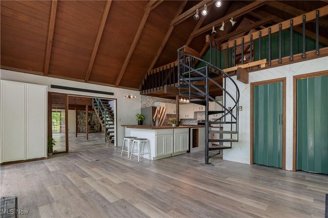 Unfurnished living room featuring stairway, high vaulted ceiling, wood finished floors, wood ceiling with exposed beams, and wooden walls | Image 9