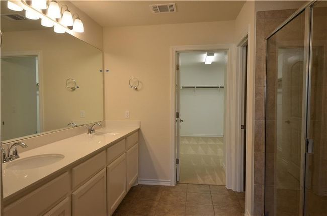 Full bathroom with double vanity, a stall shower, a spacious closet, and tile patterned flooring | Image 18