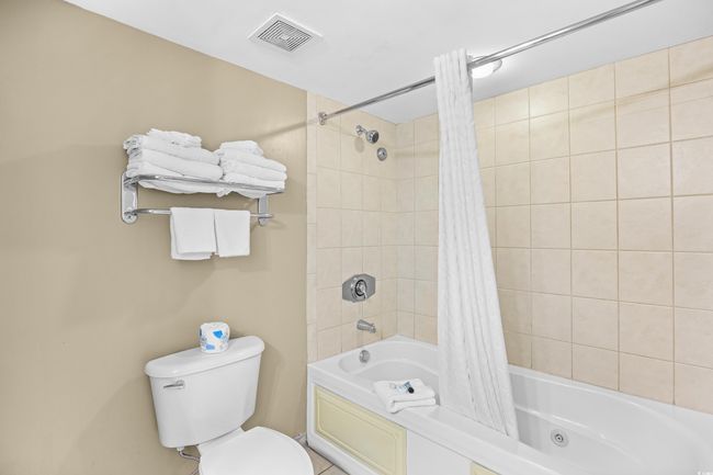 Bathroom with toilet, shower / bath combo, and visible vents | Image 24