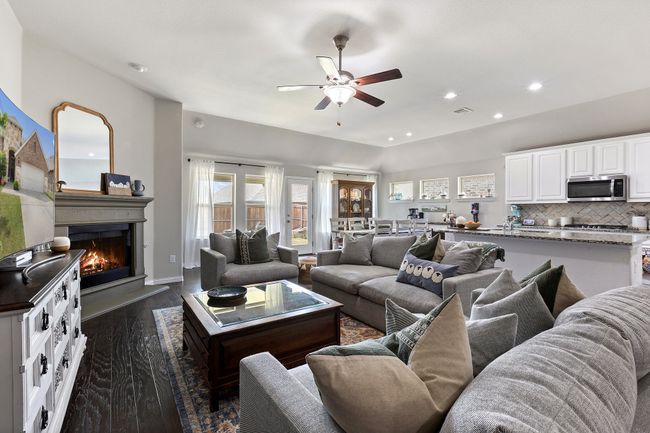 Living area with a warm lit fireplace, a ceiling fan, dark wood-type flooring, and recessed lighting | Image 6