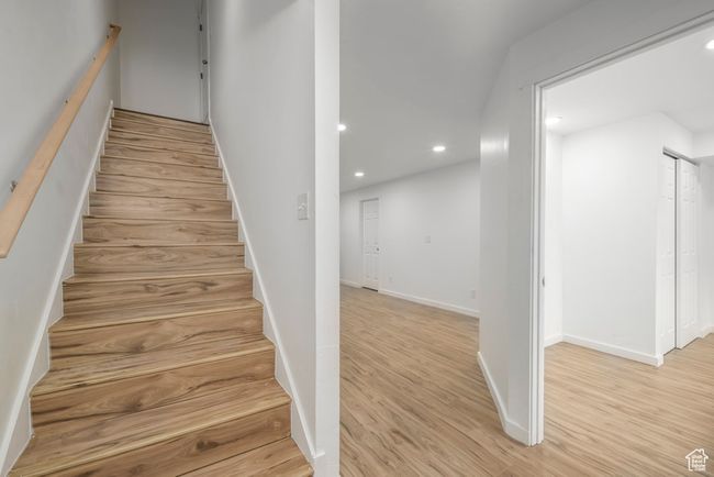 Basement stairway with it's own separate entrance from the garage entrance of the home, featuring wood finished floors, baseboards, and recessed lighting | Image 21