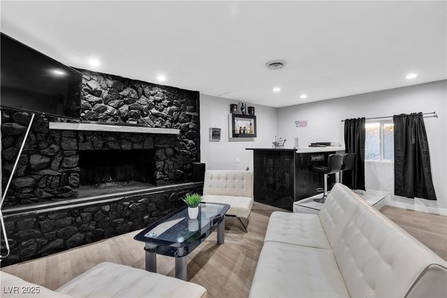 Living room with recessed lighting, a bar, a fireplace, visible vents, and light wood-style flooring | Image 19