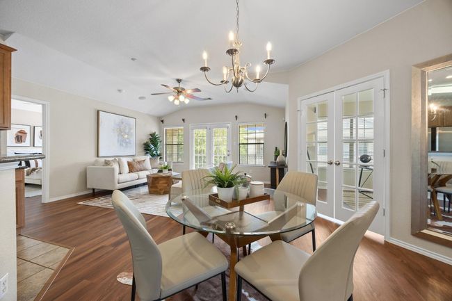 Dining space featuring vinyl wood flooring, a chandelier, and high ceilings | Image 19