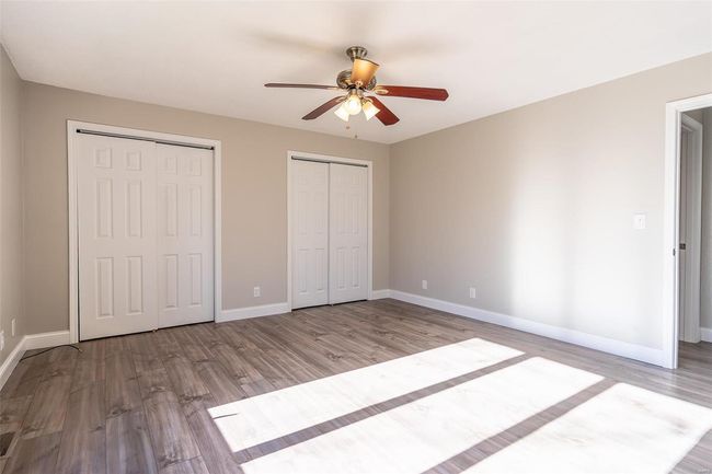 Unfurnished bedroom with ceiling fan, light wood-style floors, and two closets | Image 22