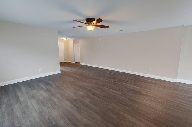 Empty room with a ceiling fan and dark wood-style flooring | Image 12