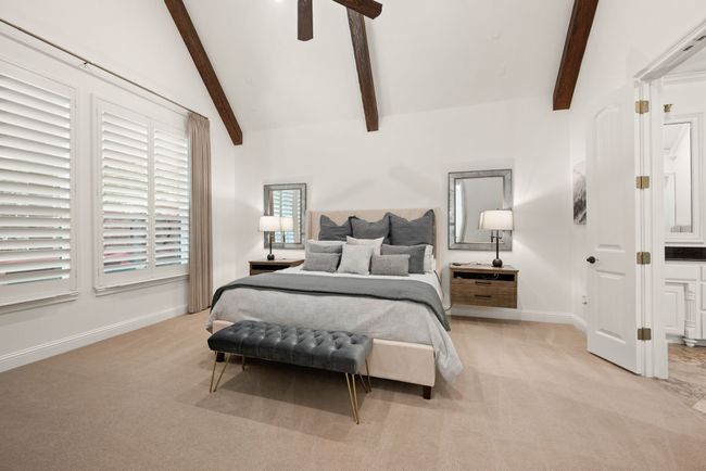 Primary Bedroom has cedar beamed ceiling with fan and light kit, wood shuttered windows, and light toned carpet | Image 17