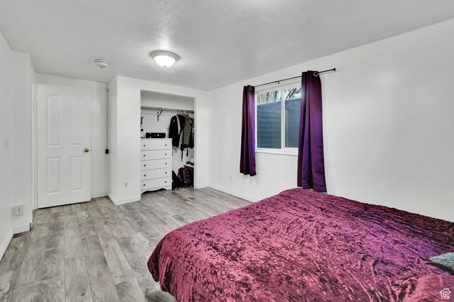 Bedroom featuring baseboards, a textured ceiling, wood finished floors, and a closet | Image 35