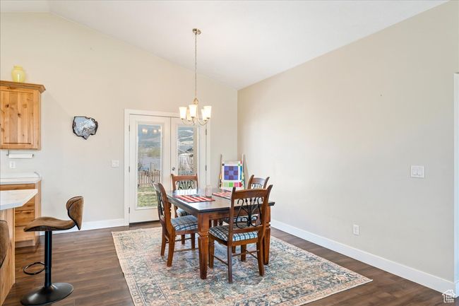 Dining area featuring a chandelier, dark wood-type flooring, high vaulted ceiling, and baseboards | Image 19