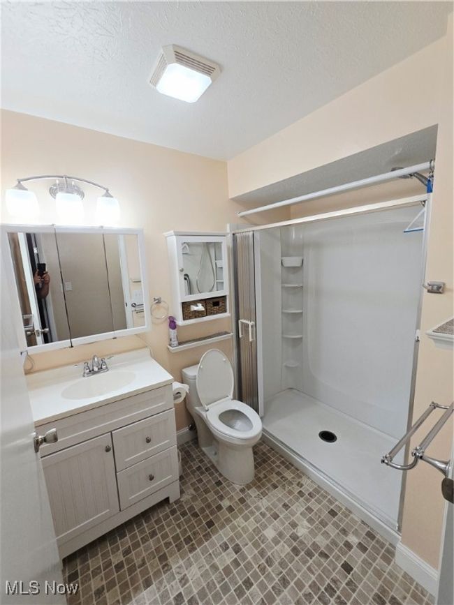 Bathroom featuring vanity, a shower stall, and a textured ceiling | Image 11