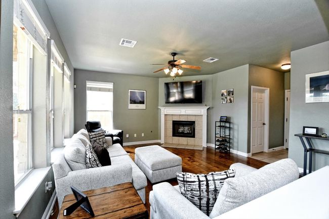 Living area featuring a ceiling fan, a tile fireplace, wood finished floors, and baseboards | Image 5