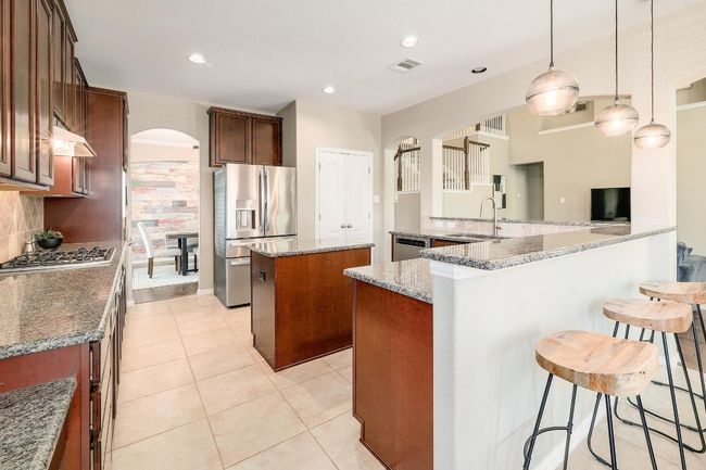 The kitchen is designed for those who love to cook and entertain with granite countertops, stainless steel appliances, and a tile backsplash | Image 4