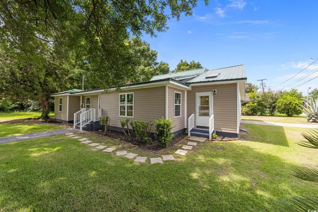 View of front of home with a metal roof and a front lawn | Image 9