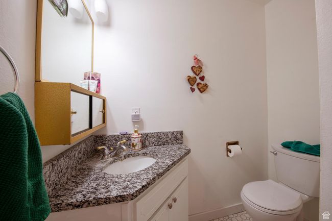 Half bathroom with baseboards, tile patterned floors, toilet, and vanity | Image 6