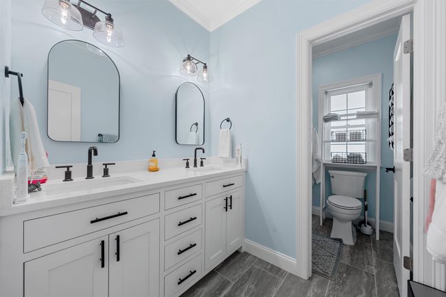 Full bathroom featuring crown molding, double vanity, a sink, and baseboards | Image 21