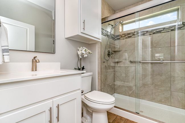 Secondary bathroom featuring toilet, vanity, a stall shower, and wood finished floors | Image 22