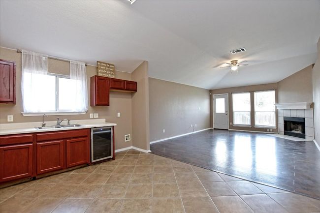 Kitchen featuring beverage cooler, a sink, ceiling fan, a tiled fireplace, and light countertops | Image 13