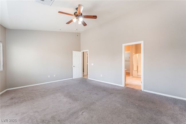 Unfurnished bedroom featuring light colored carpet, high vaulted ceiling, baseboards, connected bathroom, and a ceiling fan | Image 28
