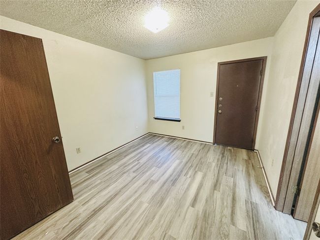Empty room with light wood-type flooring and a textured ceiling | Image 17