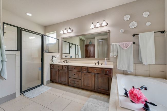 Bathroom featuring a stall shower, a bath, double vanity, and tile patterned floors | Image 28