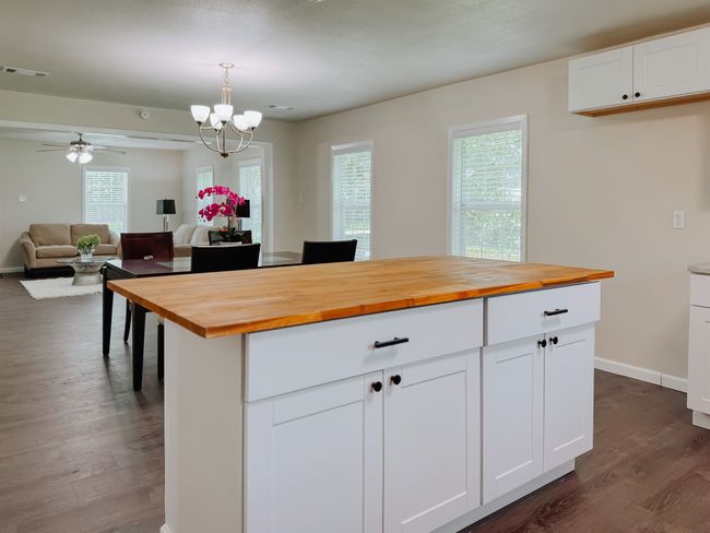 Kitchen with butcher block countertops, dark wood-style floors, a chandelier, and open floor plan | Image 13