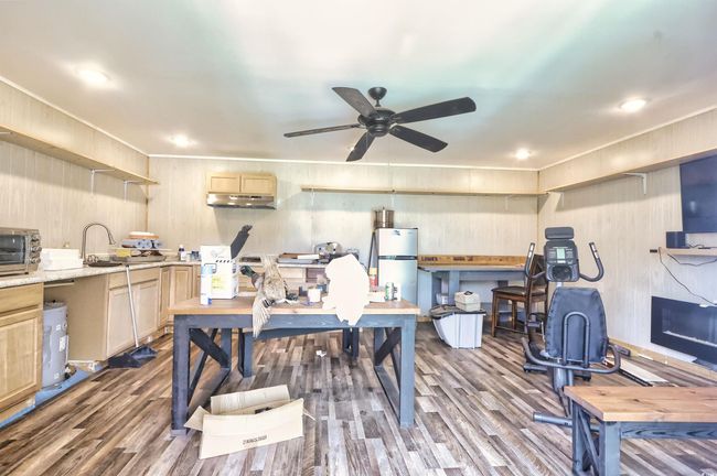 Home office with wood finished floors, ceiling fan, and wood walls | Image 27
