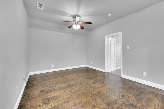 Secondary bedroom on second level with ceiling fan and wood floors. | Image 23