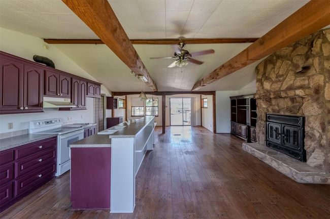 Open living/kitchen/dining with wooden beams that add charm and character. | Image 8