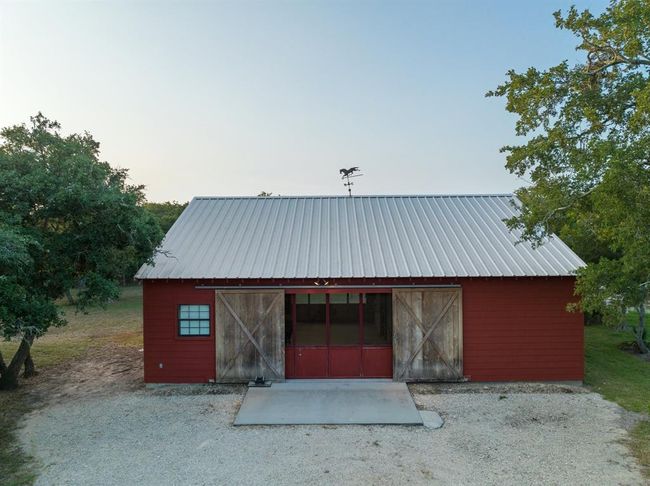 32'x 40' two stall horse stables with two turnouts. Stalls are both 14' x 14' and include corner feed bins, hay racks and automatic waterers. A shower with tankless water heater was recently built for overnight camping guests to use. A dressage arena is located near this area. | Image 44