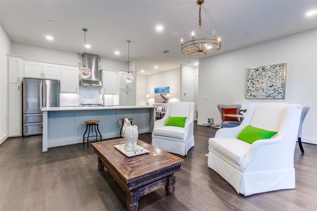 Living room with a chandelier, wide plank wood-style floors, and recessed lighting. | Image 10