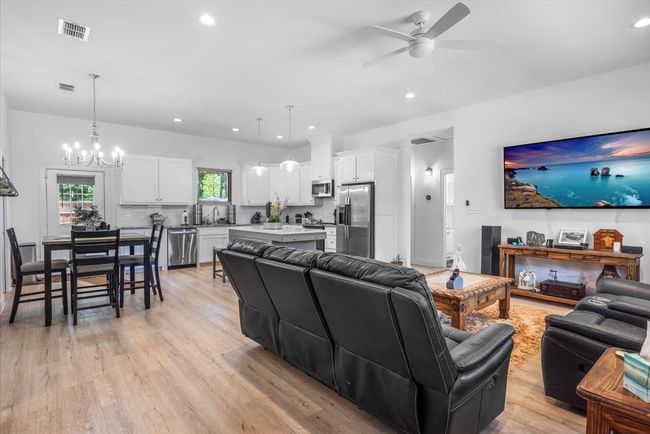 Living room featuring recessed lighting, visible vents, light wood-style floors, and ceiling fan with notable chandelier | Image 7