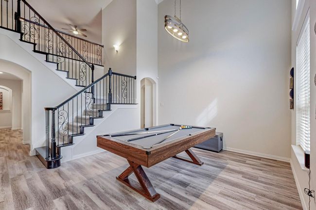 Rec room with arched walkways, a towering ceiling, wood finished floors, ceiling fan, and billiards table | Image 20