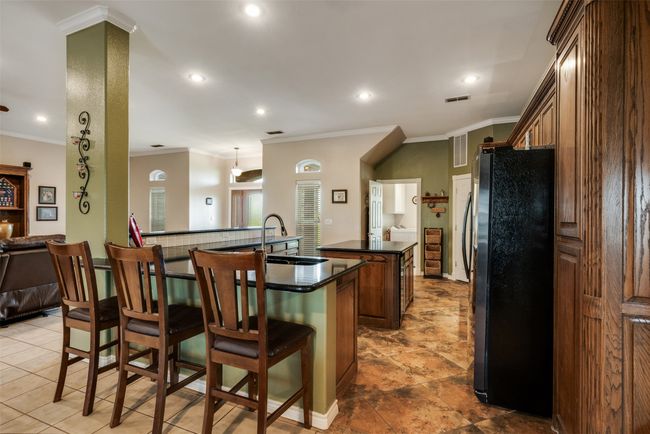 Kitchen with dark countertops, a sink, freestanding refrigerator, visible vents, and a kitchen island | Image 9