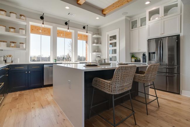 Kitchen featuring a center island, stainless steel appliances, a kitchen breakfast bar, blue cabinets, and white cabinets | Image 12