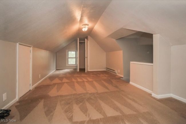 Additional living space featuring carpet, a baseboard radiator, and vaulted ceiling | Image 6