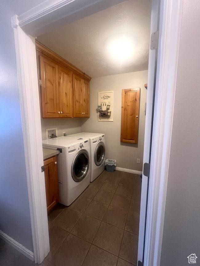 Laundry area featuring cabinet space, baseboards, dark tile patterned flooring, and washer and dryer | Image 40