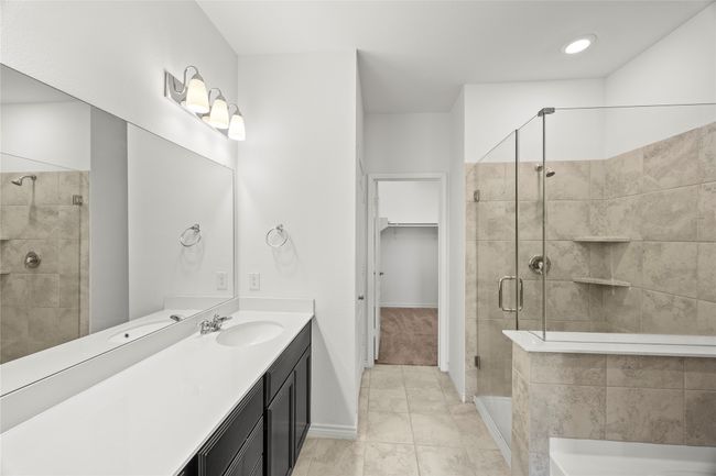 Bathroom featuring a shower stall, vanity, a walk in closet, a tub, and baseboards | Image 23