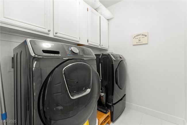 Laundry area featuring independent washer and dryer, cabinet space, baseboards, and light tile patterned floors | Image 35