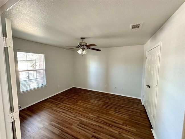 Spare room with a ceiling fan, a textured ceiling, baseboards, visible vents, and dark wood-type flooring | Image 8