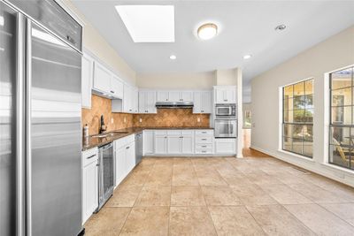 Kitchen featuring a skylight, sink, beverage cooler, white cabinetry, and built in fridge and appliances | Image 2