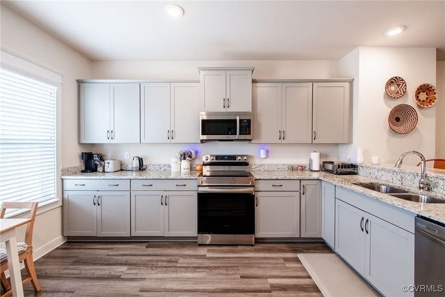 Kitchen with appliances with stainless steel finishes, healthy amount of natural light, light wood-style floors, light stone countertops, and recessed lighting | Image 8