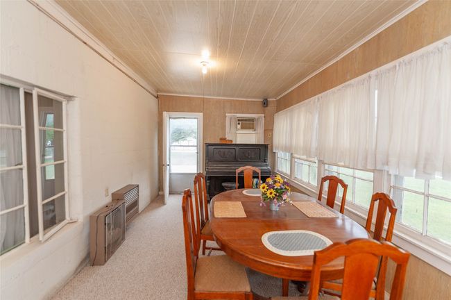 Dining area with a wall mounted AC, ornamental molding, wooden ceiling, and carpet floors | Image 17