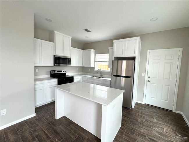 Kitchen featuring appliances with stainless steel finishes, a sink, dark wood-style floors, and a kitchen island | Image 6