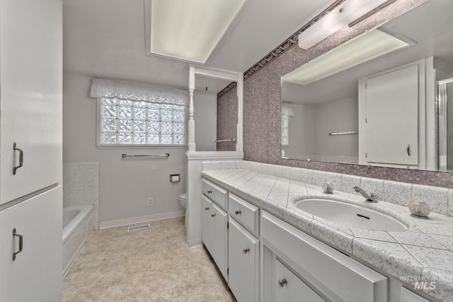 Bathroom with tiled vanity, a bath, and a shower with door | Image 23