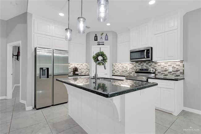Kitchen with stainless steel appliances, light marble finish floors, white cabinetry, decorative backsplash, and recessed lighting | Image 10