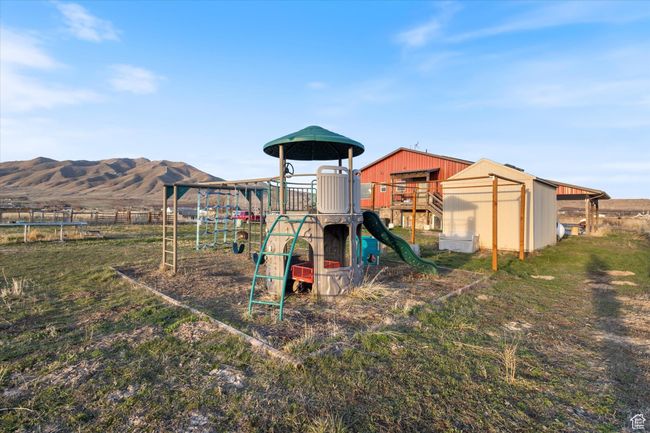 Community playground with a mountain view, a trampoline, and fence | Image 39